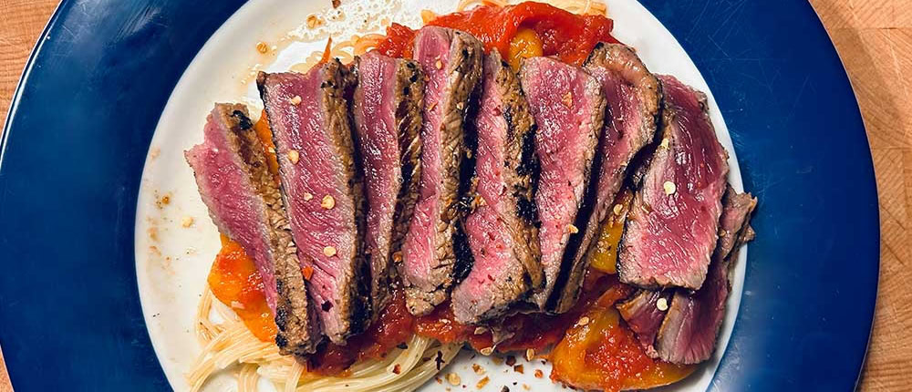 Saftiges Rindersteak auf Pasta mit Tomatensauce und Gewürzen.