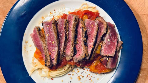 Saftiges Rindersteak auf Pasta mit Tomatensauce und Gewürzen.