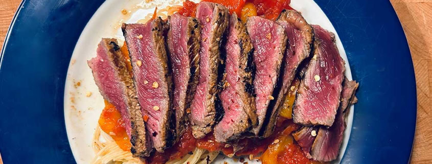 Saftiges Rindersteak auf Pasta mit Tomatensauce und Gewürzen.